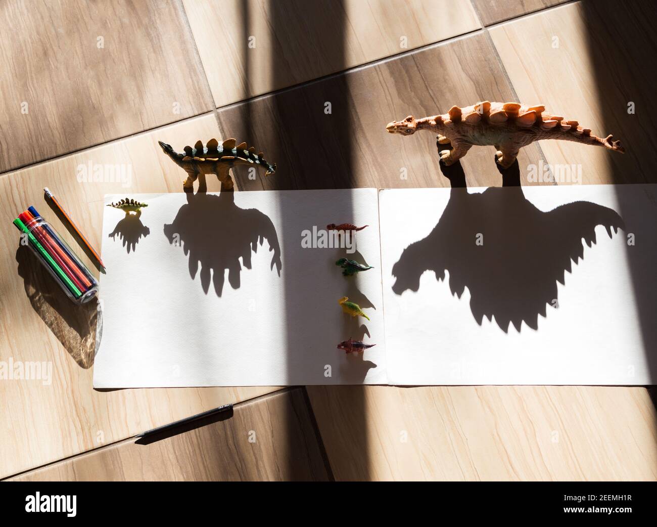 Playing with light and shadow. Outline the shadow of the toy dinosaur figure. Childhood, games for the development of children's creativity at home Stock Photo