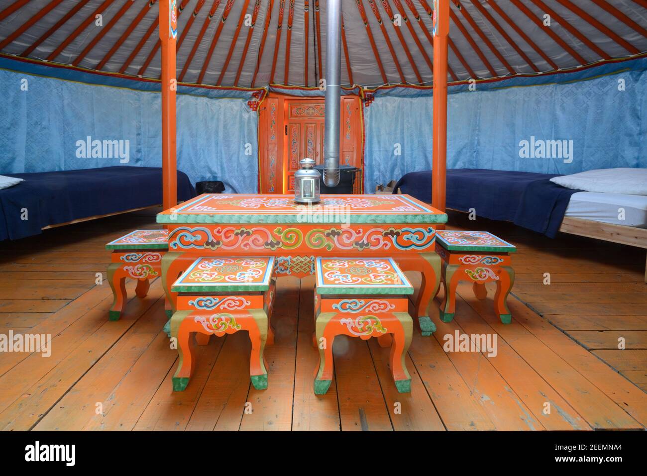 Interior of a Mongolian Yurt or Ger with Painted Furniture including low Table & Chairs or Stools & Wood Burning Stove Stock Photo