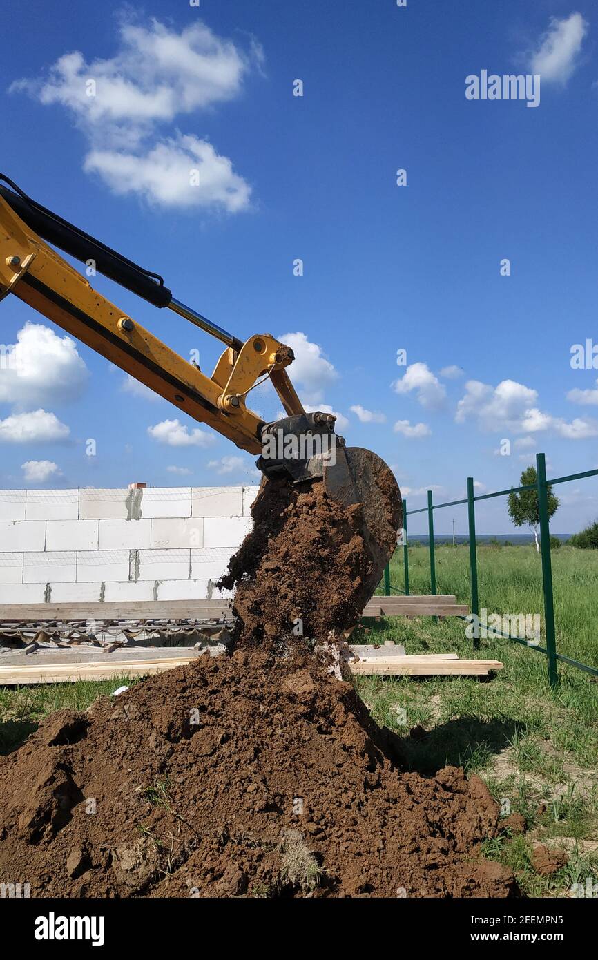The yellow excavator digs a trench, construction works by means of ...