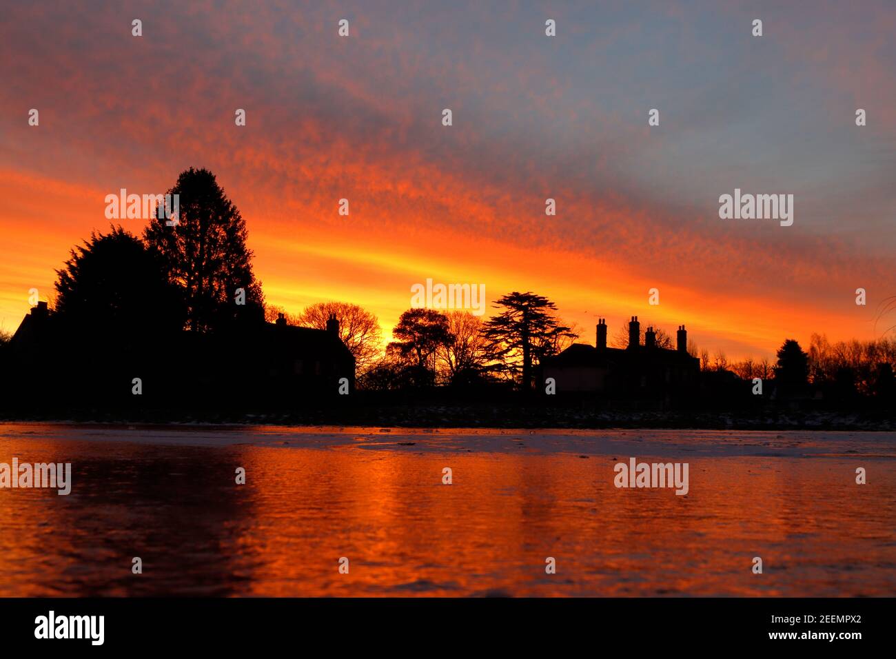 A red and yellow sunrise over the frozen pond at Matching Green Village