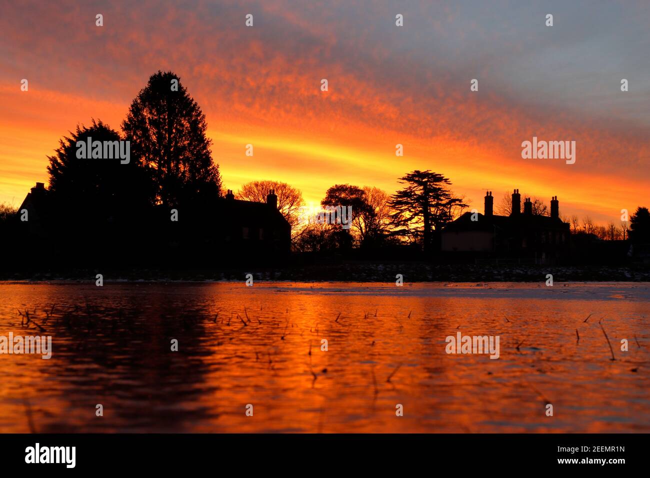 A red and yellow sunrise over the frozen pond at Matching Green Village