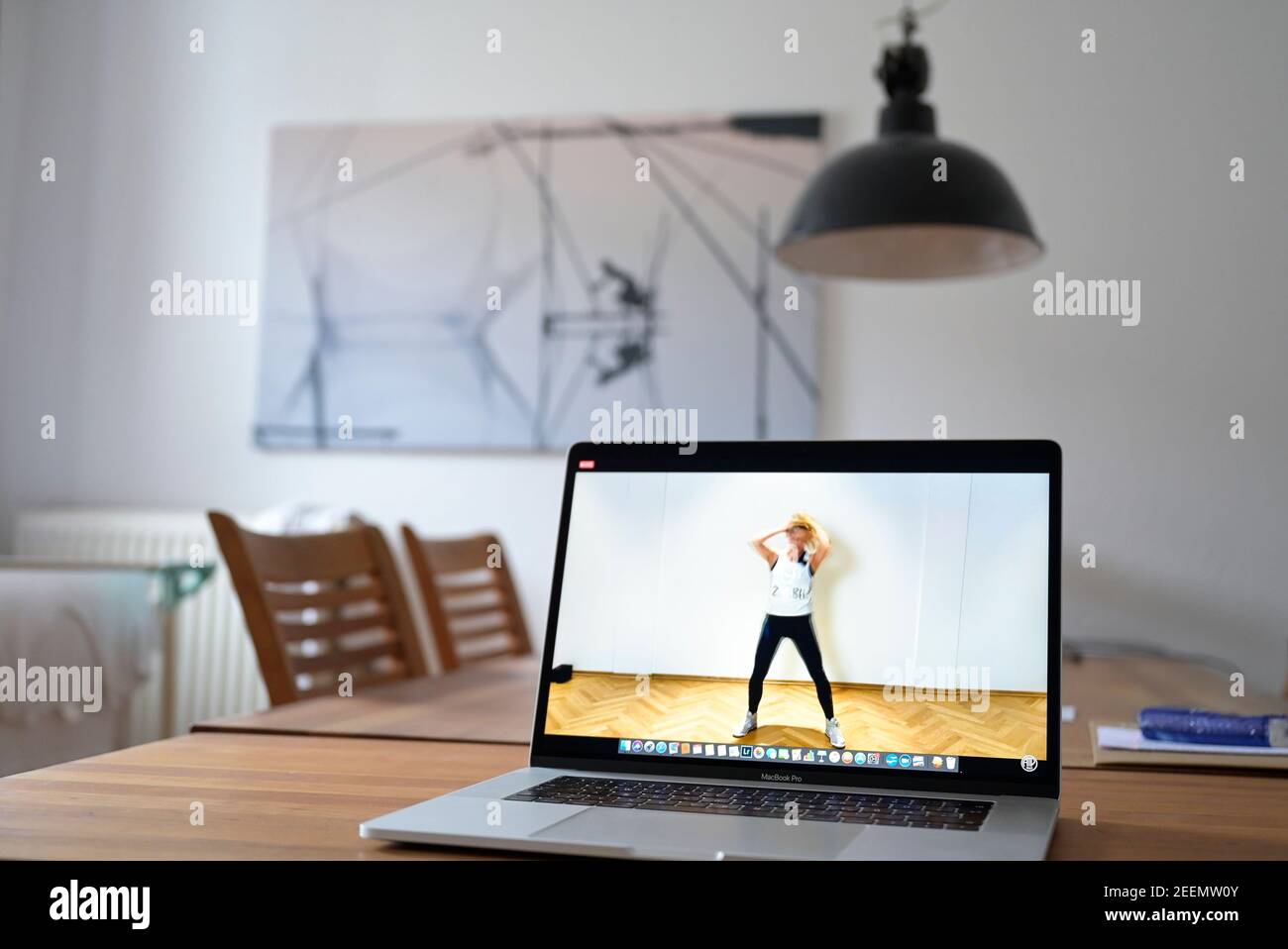GERMANY, Hamburg, corona pandemic, young woman doing sports at home with online streaming of sport club, apple macbook screen with Zumba dance session Stock Photo