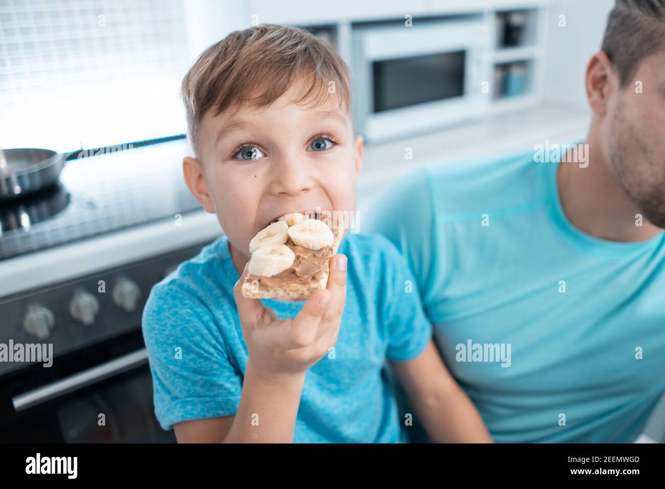 happy kid boy and father eating healthy peanut butter toast at home