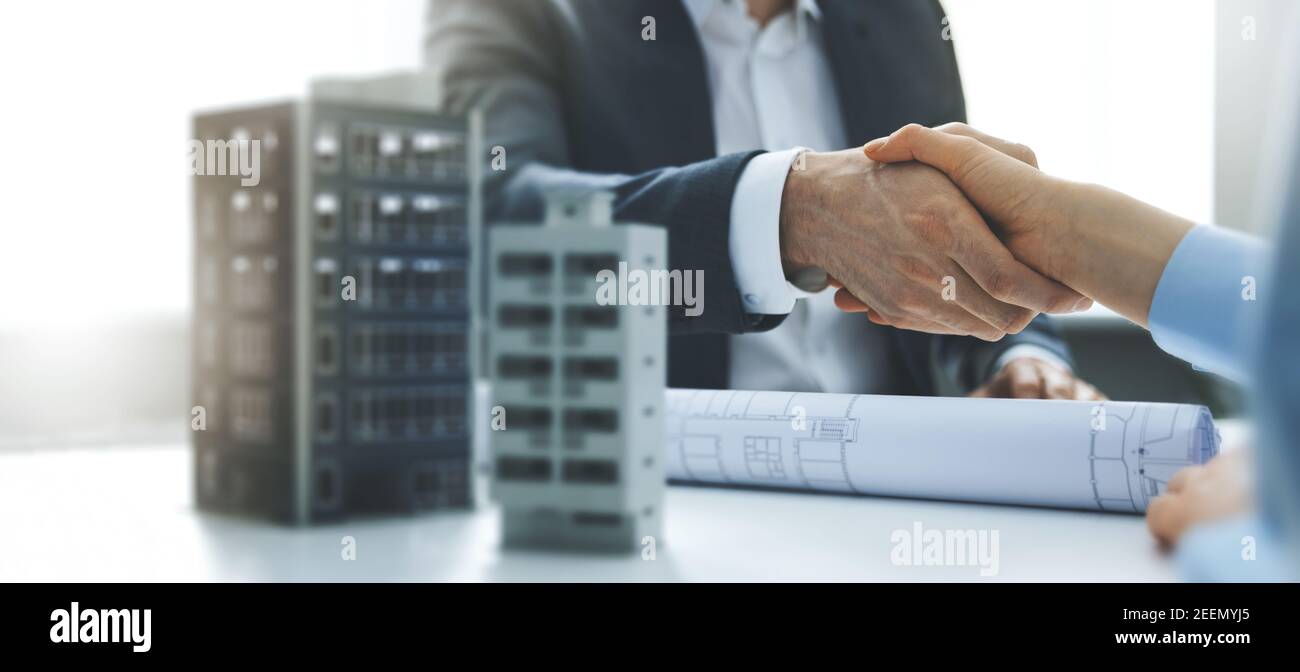 housing development and investment business - businessmen handshake after agreement of apartment building construction. banner copy space Stock Photo