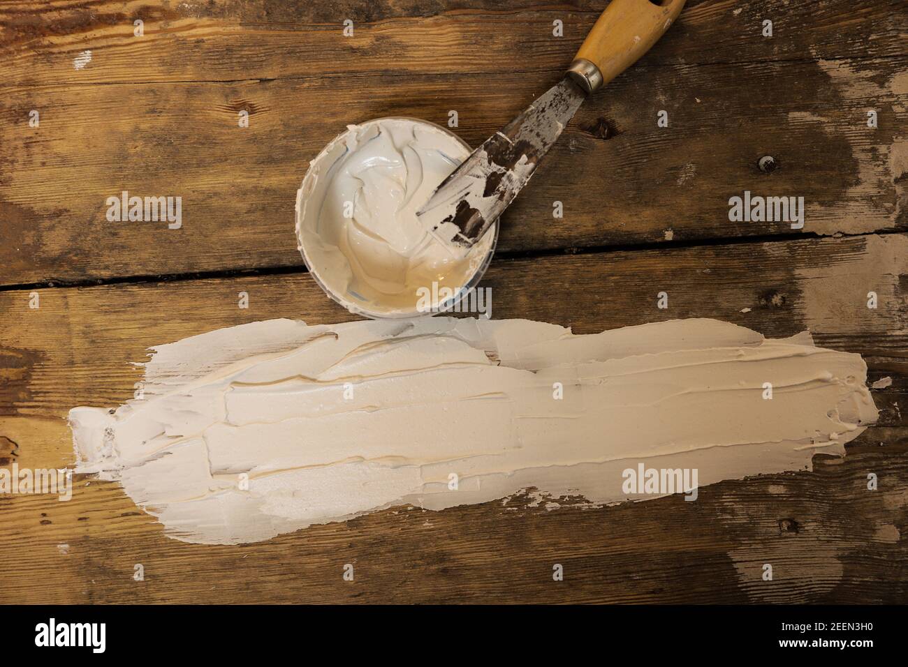 Top view of white putty and putty knife on the old wooden floor Stock