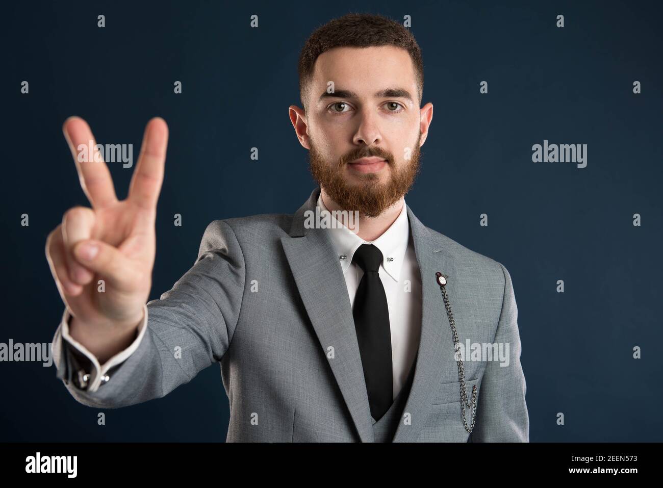 Young businessman showing peace sign wearing a grey suit Stock Photo