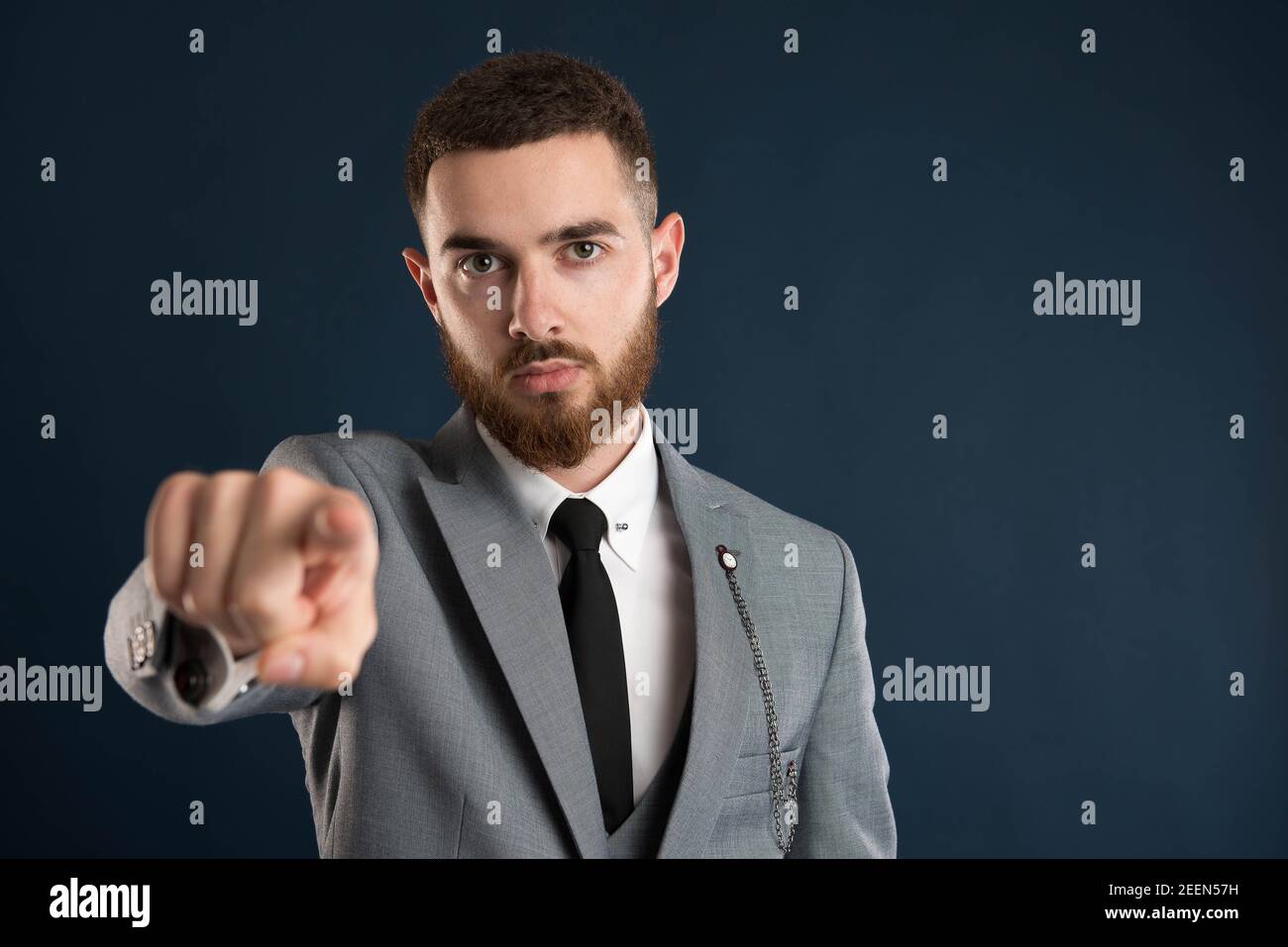 Serious young businessman pointing at you wearing a grey suit and black tie Stock Photo