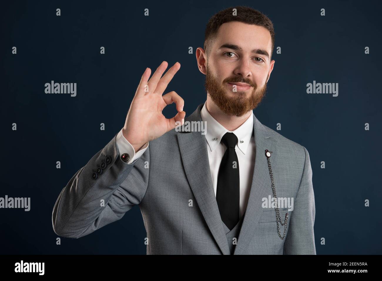 Happy businessman saying ok wearing a grey suit and black tie Stock Photo