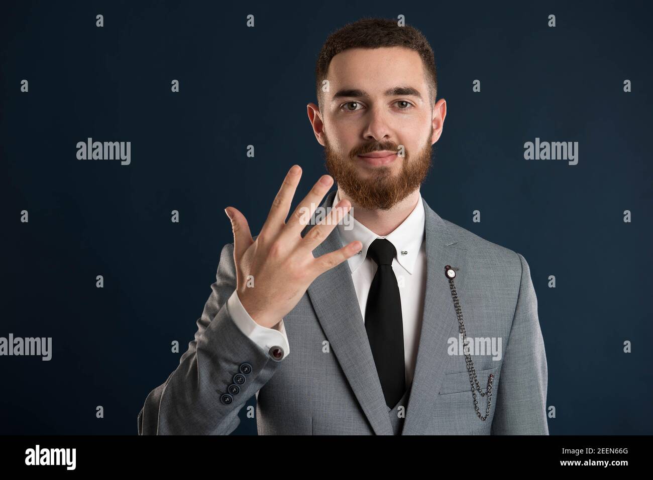 Happy businessman showing the number five wearing a black tie and a grey suit Stock Photo