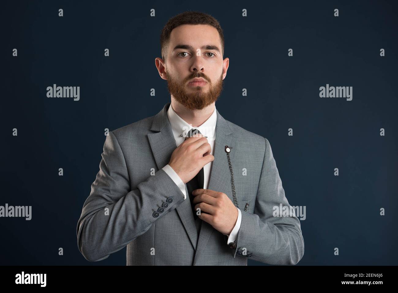 Handsome businessman fixing his black tie wearing a grey jacket Stock Photo