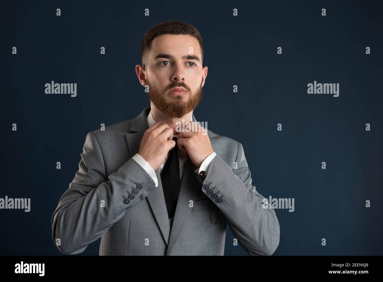 Handsome businessman fixing his black tie and shirt wearing a grey jacket Stock Photo