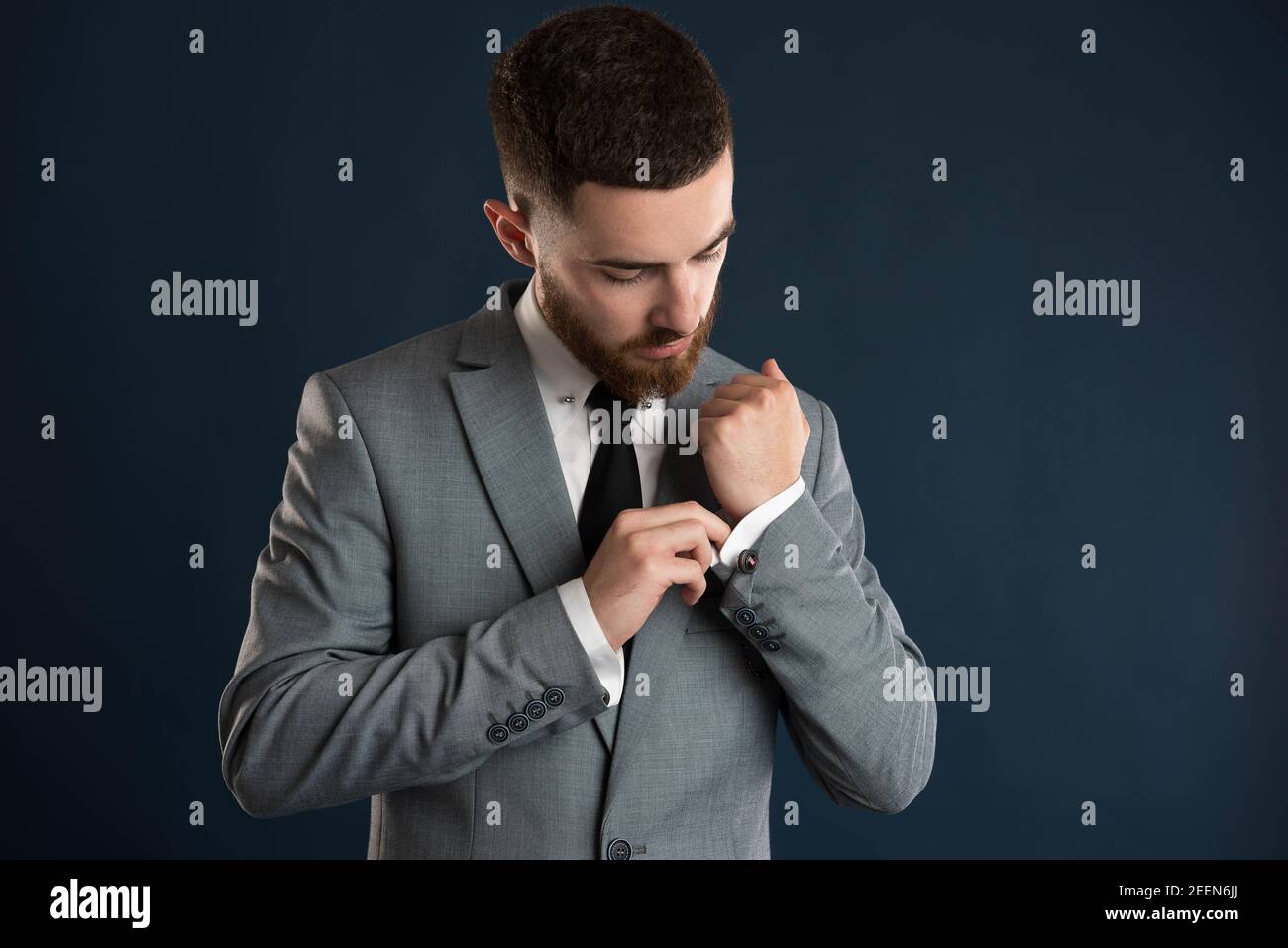 Handsome businessman fixing his shirt wearing a black tie and grey jacket Stock Photo