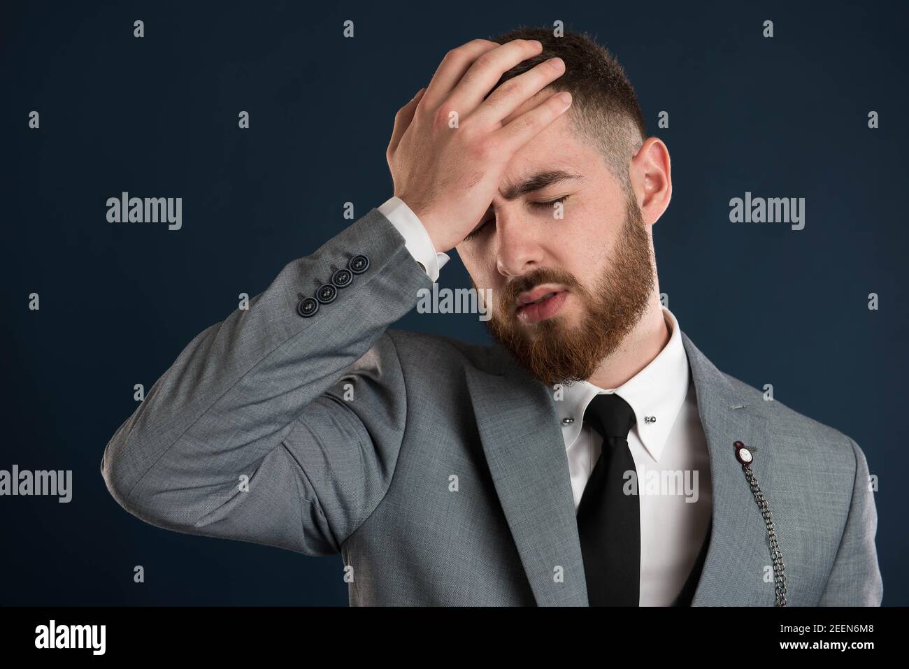 Handsome businessman having a headache wearing a black tie and a grey suit Stock Photo