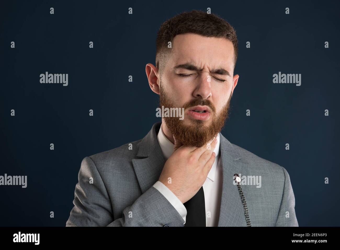 White collar worker having troat pain wearing a black tie and grey suit Stock Photo