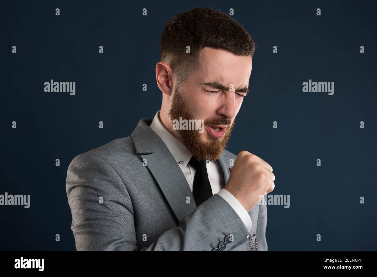 Handsome young businessman cauching wearing a black tie and a grey suit Stock Photo