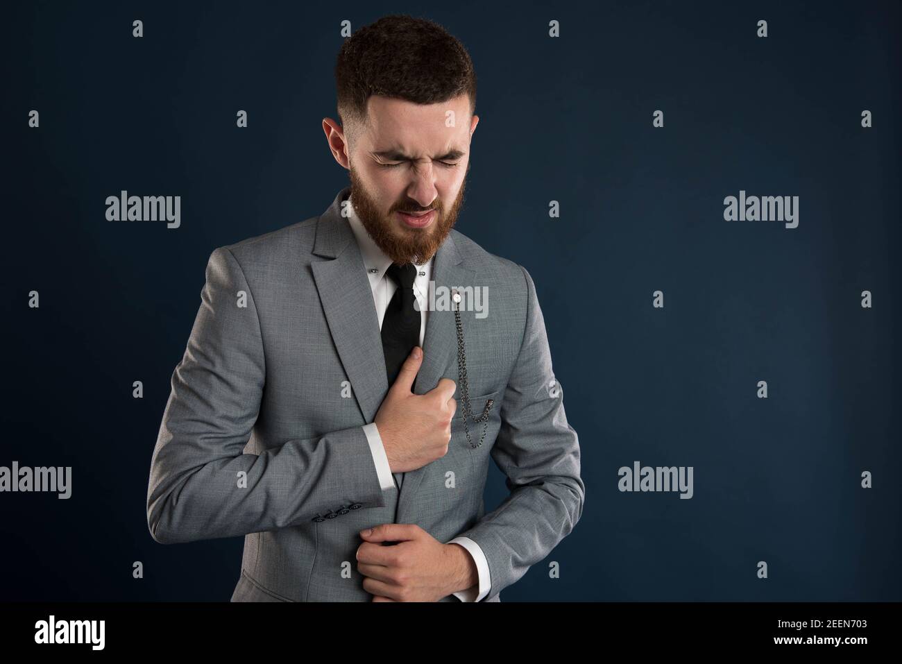 Handsome young white collar worker with chest pain wearing a grey jacket Stock Photo