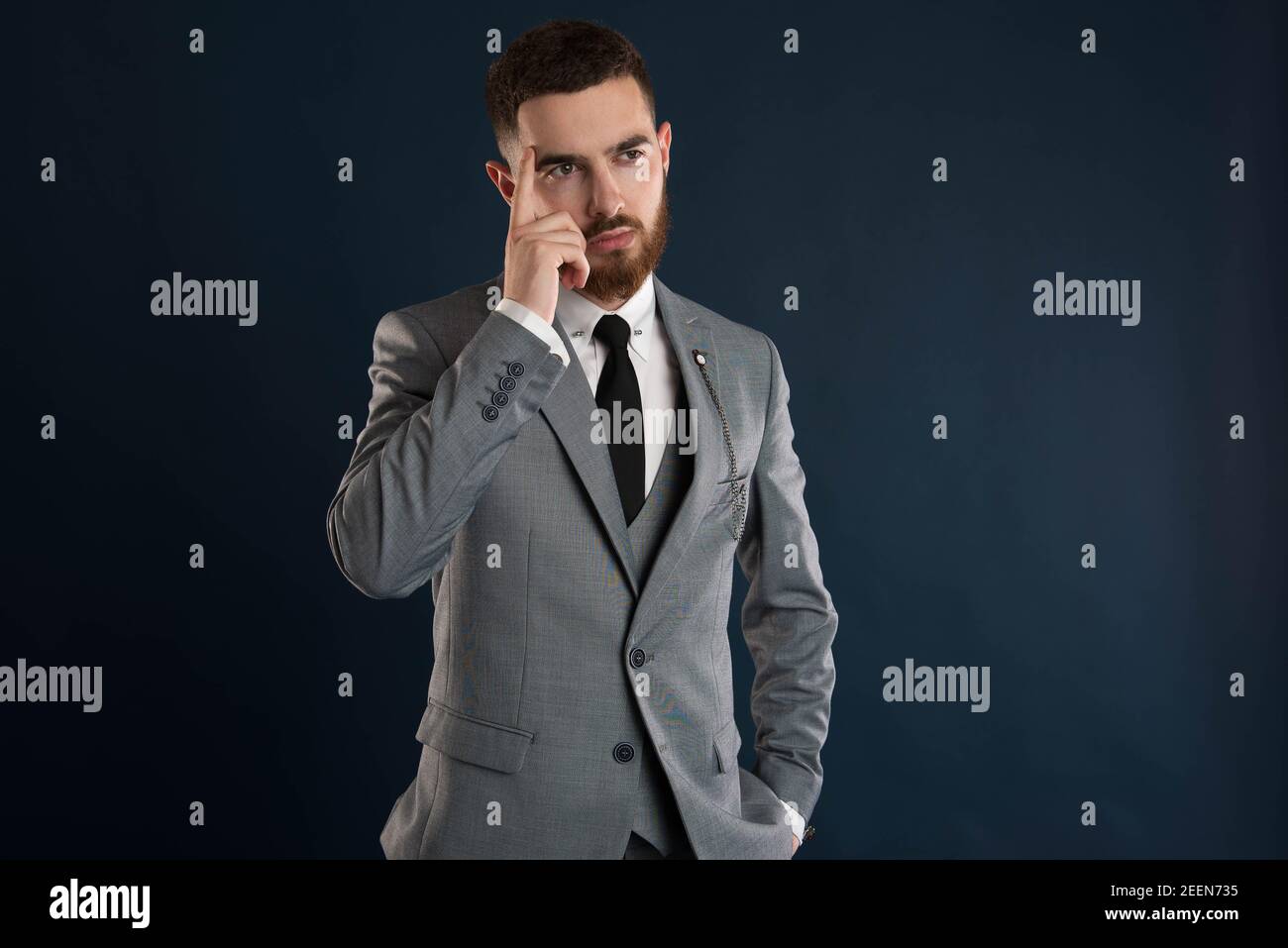 Handsome young businessman thinking about a deal wearing a grey suit and black tie Stock Photo