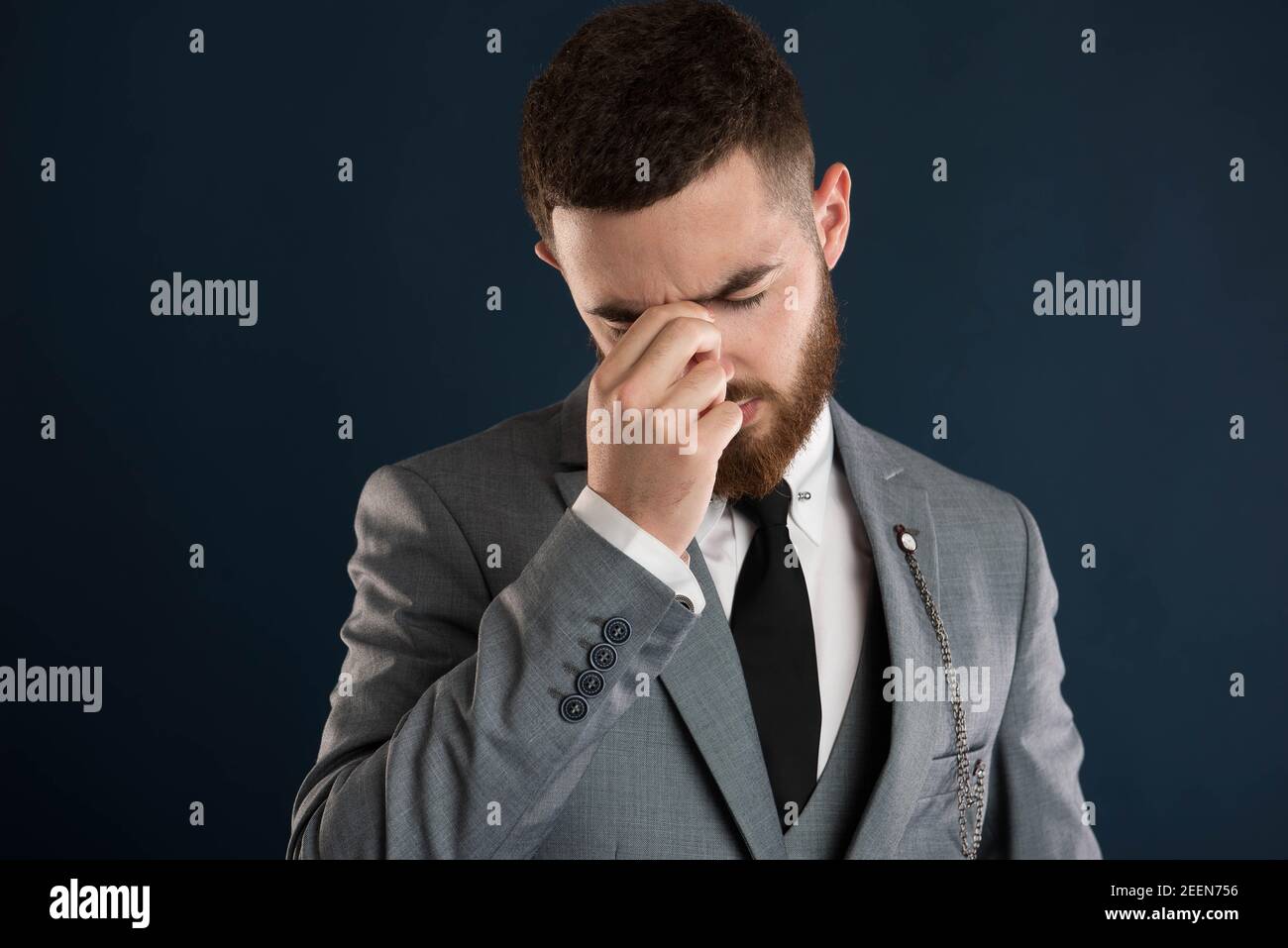 Handsome young businessman having a bad day wearing a grey suit and black tie Stock Photo