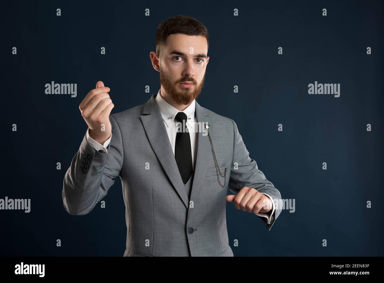 Upset young entrepreneur saying that time is money wearing a grey suit and black  tie Stock Photo