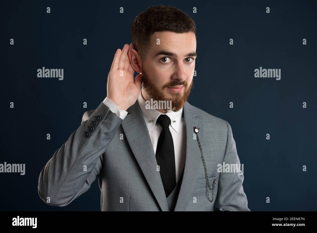 Young adult businessman listening to what you are saying wearing a grey suit and black tie Stock Photo