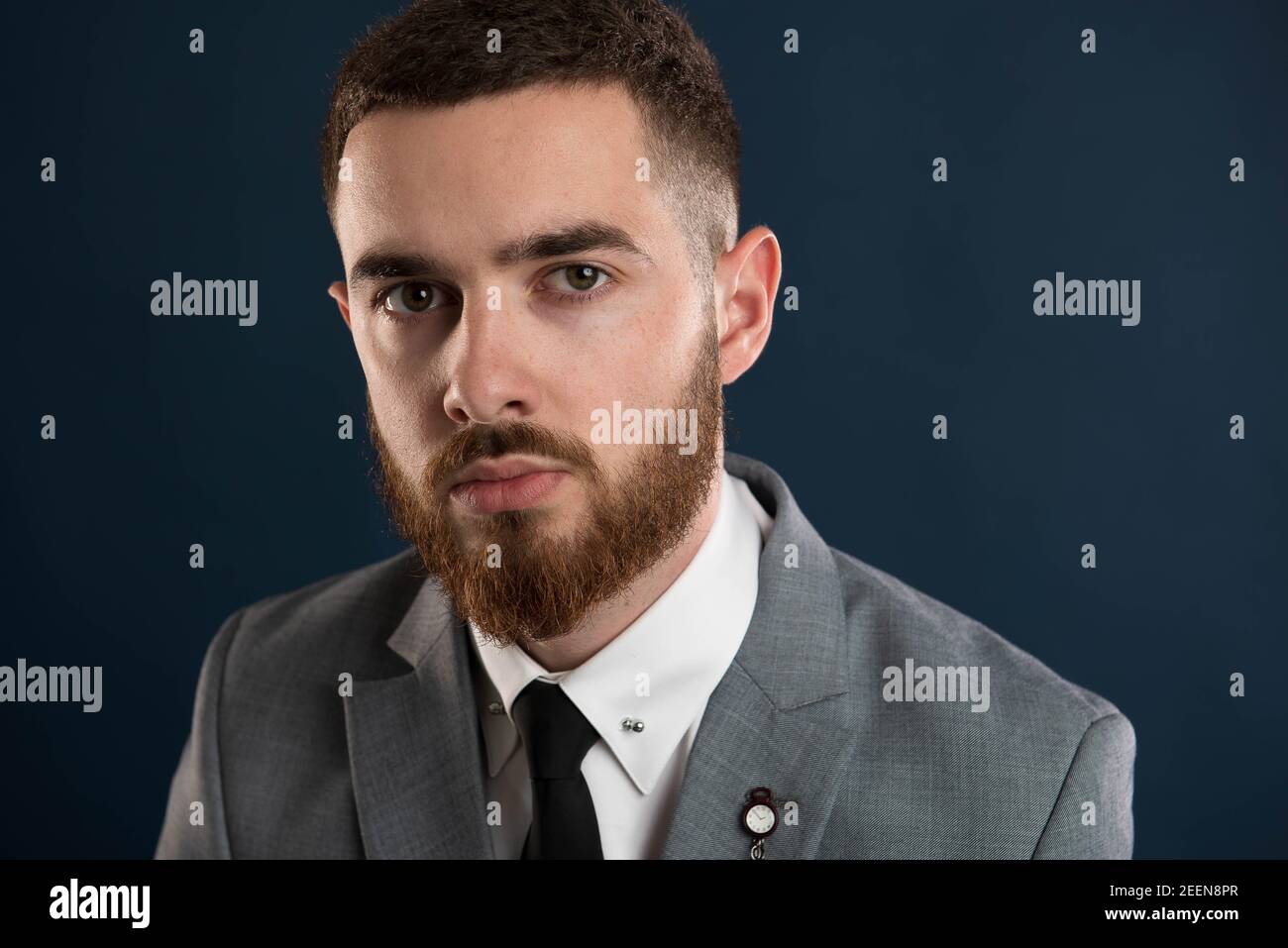Portrait of a young gentleman  wearing a grey suit and sporting a mustache and beard Stock Photo