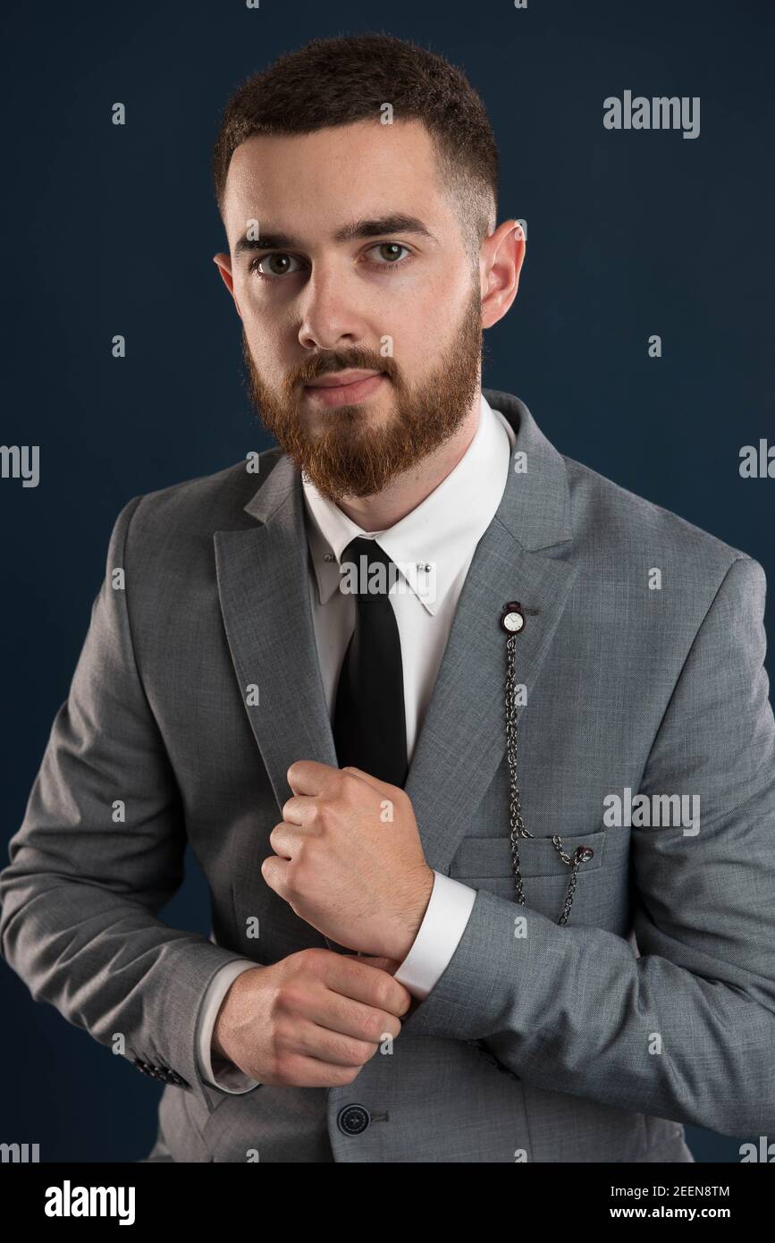 Portrait of a young entrepreneur fixing his sleeve wearing a grey suit and black tie Stock Photo
