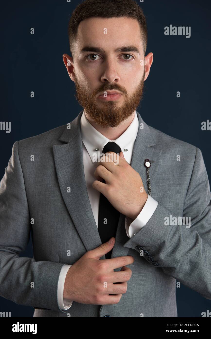 Portrait of a young businessman fixing his black tie wearing a grey suit Stock Photo