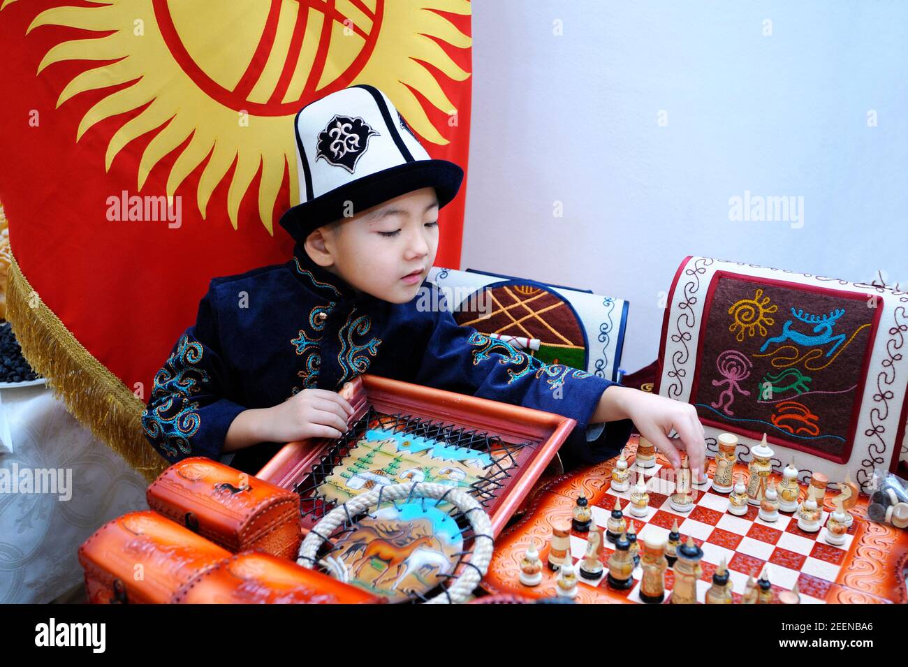 Asian little boy in a native Kyrgyz hat playing chess. Festival of Oriental culture. March 20, 2018. Kyiv, Ukraine Stock Photo