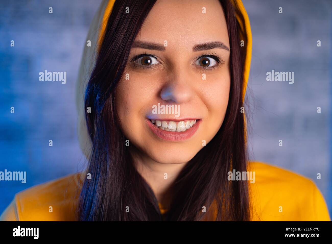 A young woman in a fashionable yellow hoodie. Portrait of a beautiful woman in a yellow hoodie against background of brick wall. Stock Photo