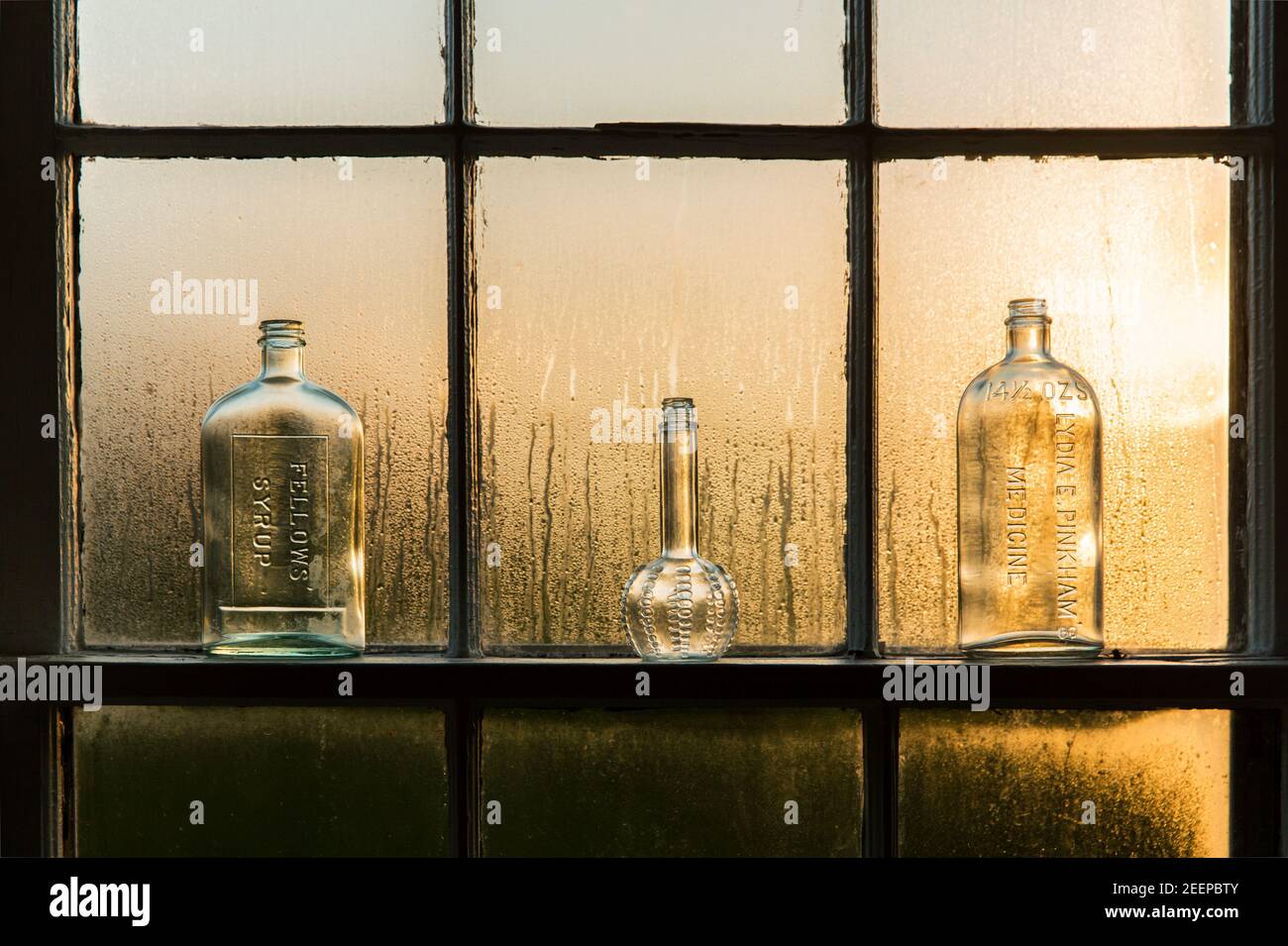 antique bottles on a window sill backlight by morning sun. Stock Photo