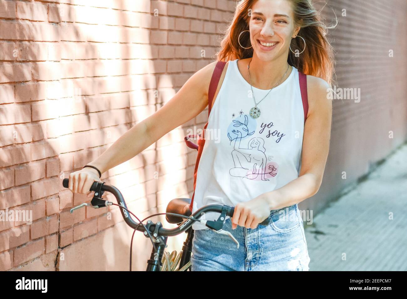 Woman with bicyle walking on street Stock Photo