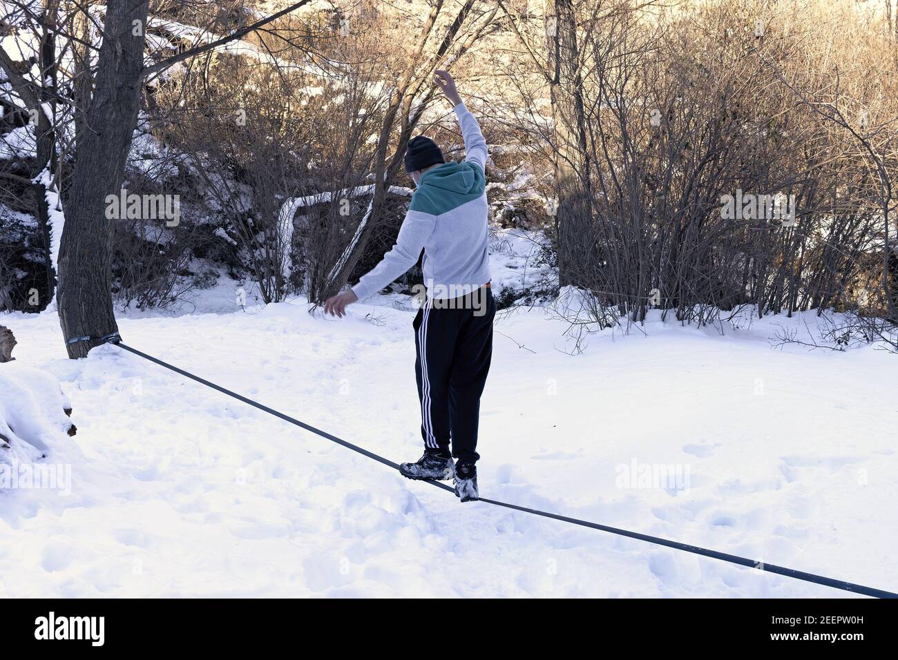 A young teenager balances a tightrope in the snow Stock Photo