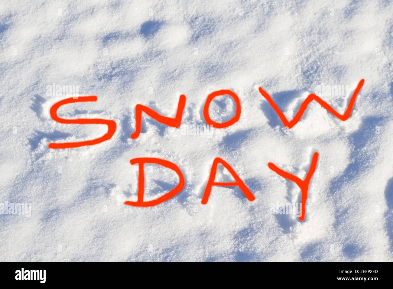 SNOW DAY written in bright red capital letters in fresh snowfall signifies No School and school closure due to dangerous weather conditions. Stock Photo