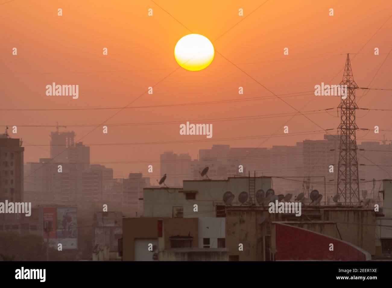 Mumbai, Maharashtra, India - March 2017: The setting sun in the sky above a skyline of buildings in a suburb in Mumbai city. Stock Photo