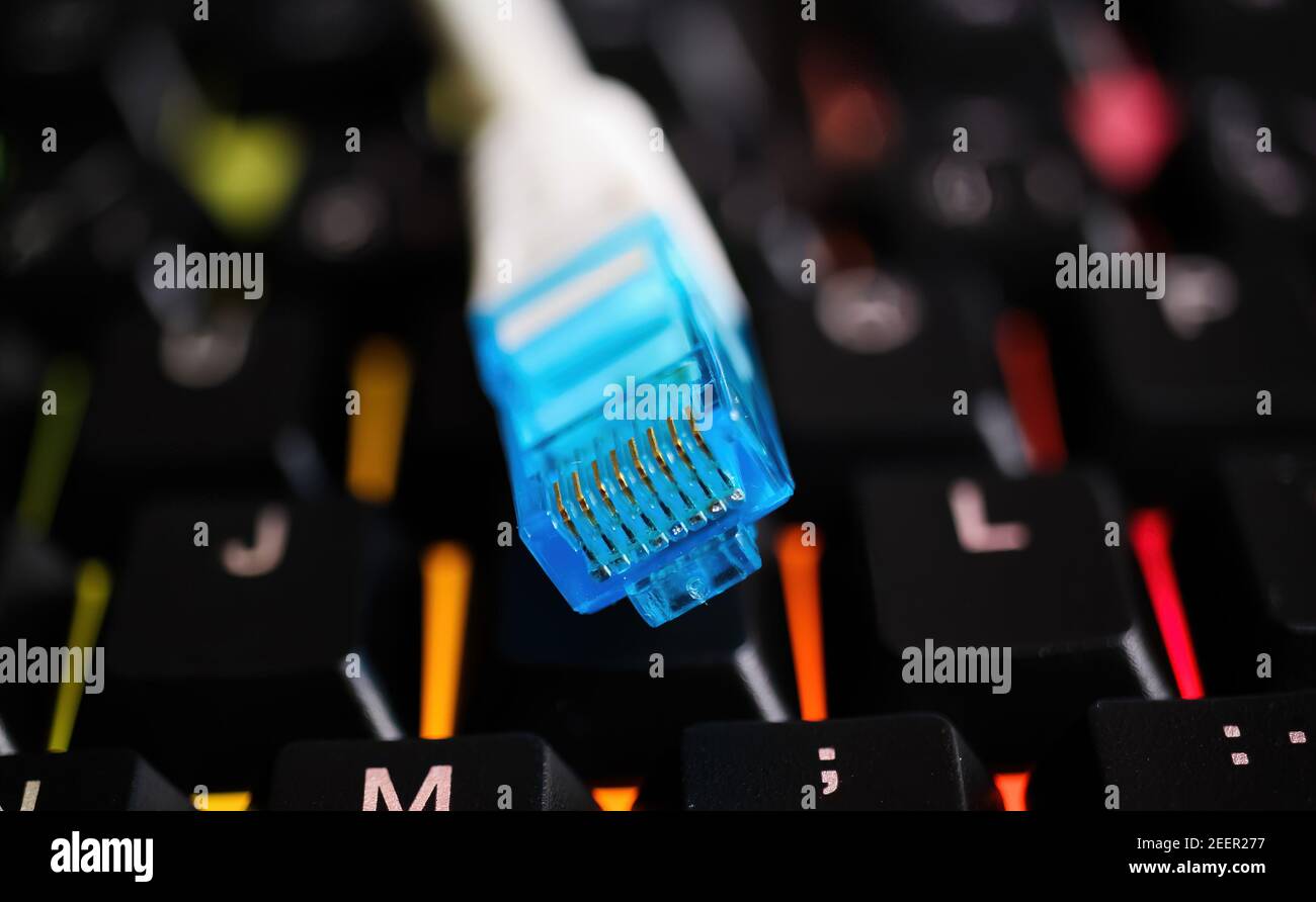 Makro closeup of isolated blue white network connector cable on illuminated computer keyboard