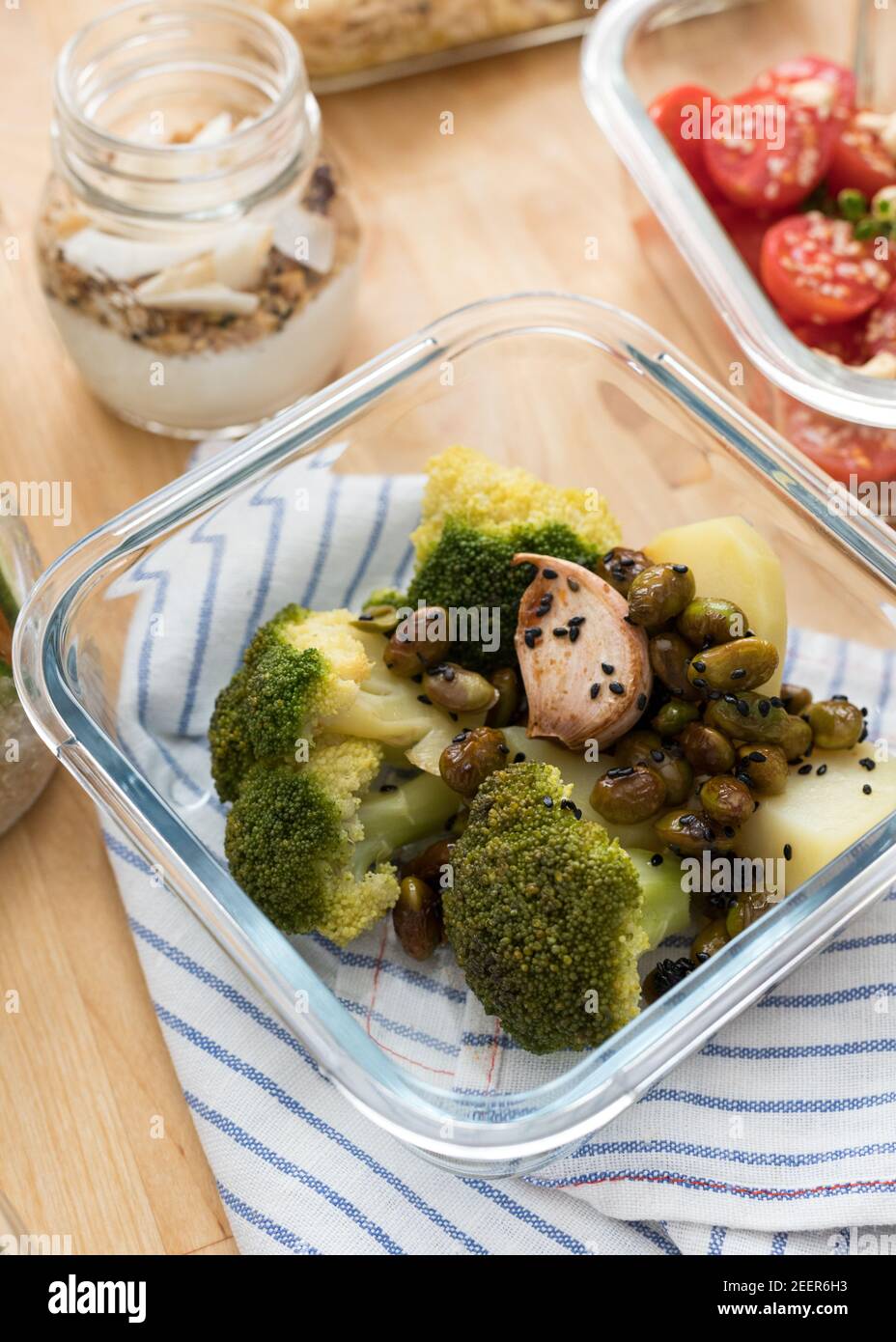 Closeup view of a glass container full of veggie food. It is next to ...
