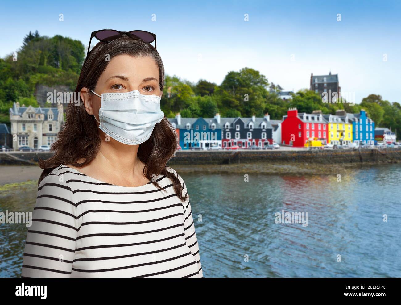 Travelling during the corona or covid pandemic: woman tourist wearing protective face mask at Tobermory, Mull Island, Scotland. Stock Photo