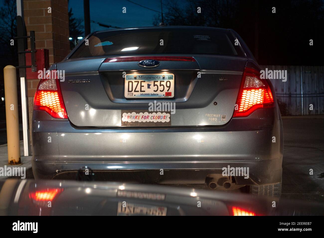 Sign on car bumper sticker saying "I Brake for Clouds". St Paul Minnesota MN USA Stock Photo