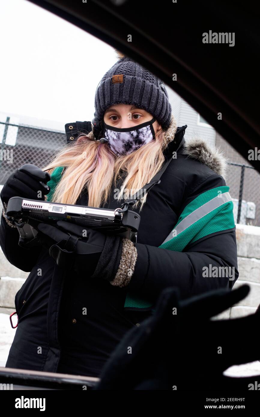 Masked woman taking a coffee order at Starbucks drive-thru during Covid Pandemic in frigid weather. St Paul Minnesota MN USA Stock Photo