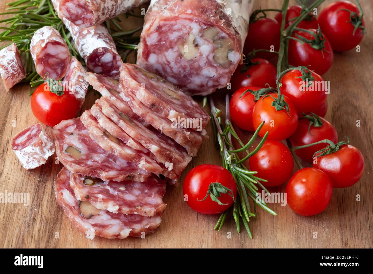 Sliced Airdried salami with rosemary and cherry tomatoes wood