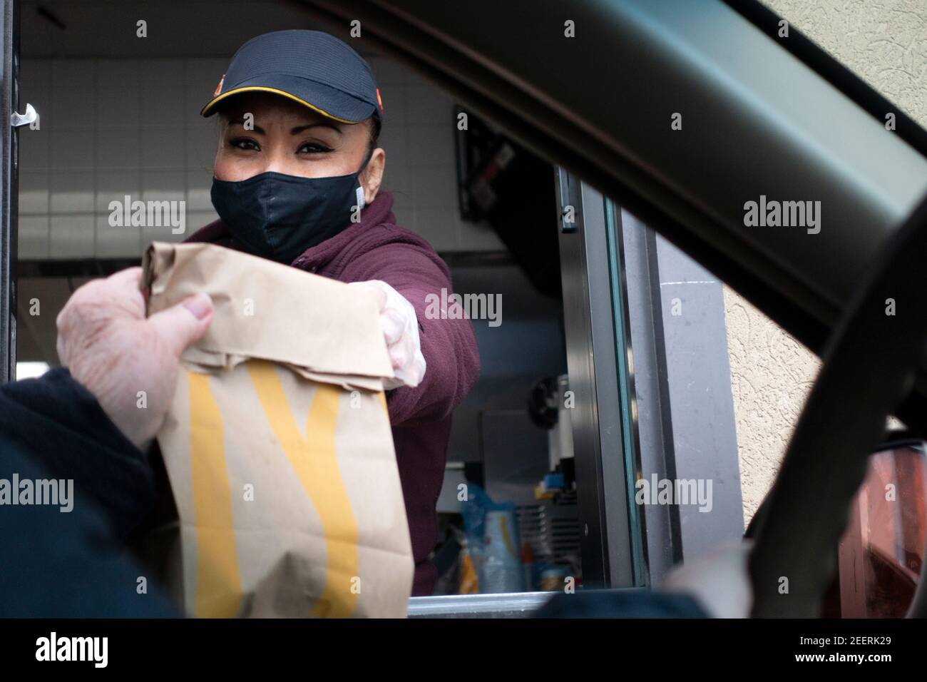 McDonald's food service worker masked handing food to customer in car during he COVID-19 Pandemic. St Paul Minnesota MN USA Stock Photo