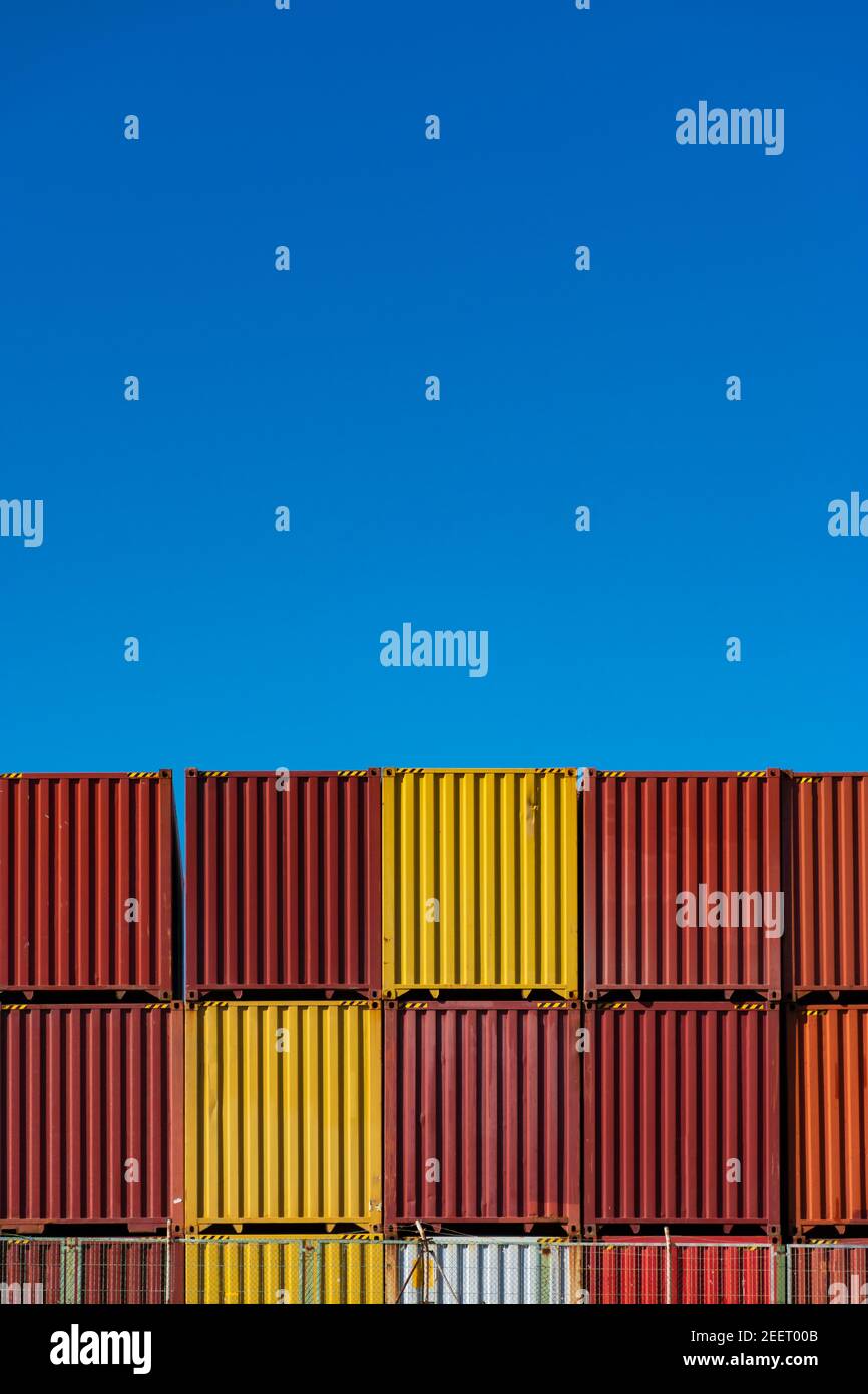 Piled red and yellow containers for merchandise transport, without texts or marks, and blue clear sky Stock Photo