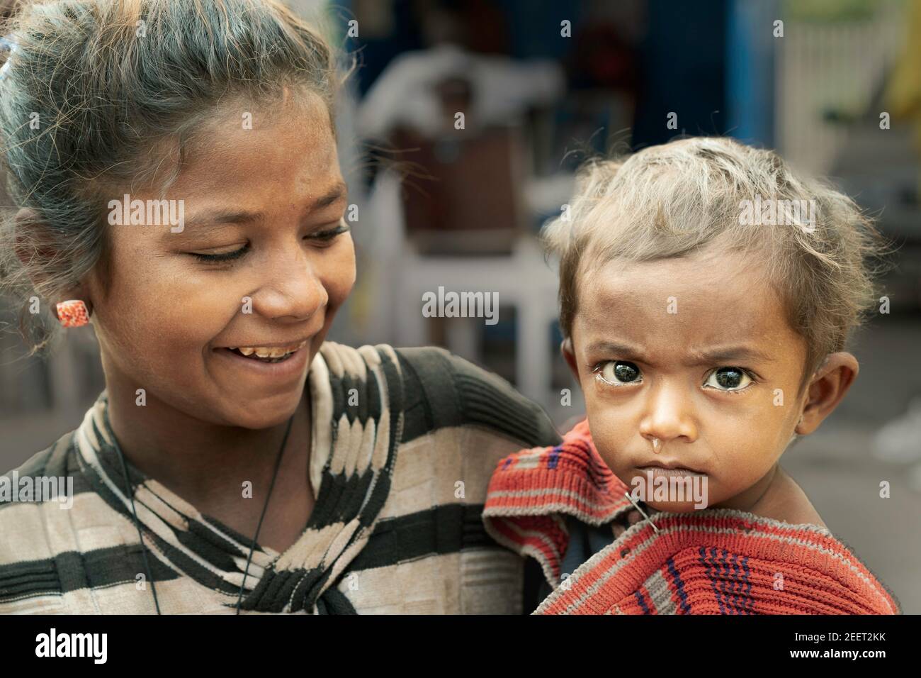 Young woman holding crying child with runny nose and living on streets in Udaipur, Rajasthan, India. Stock Photo