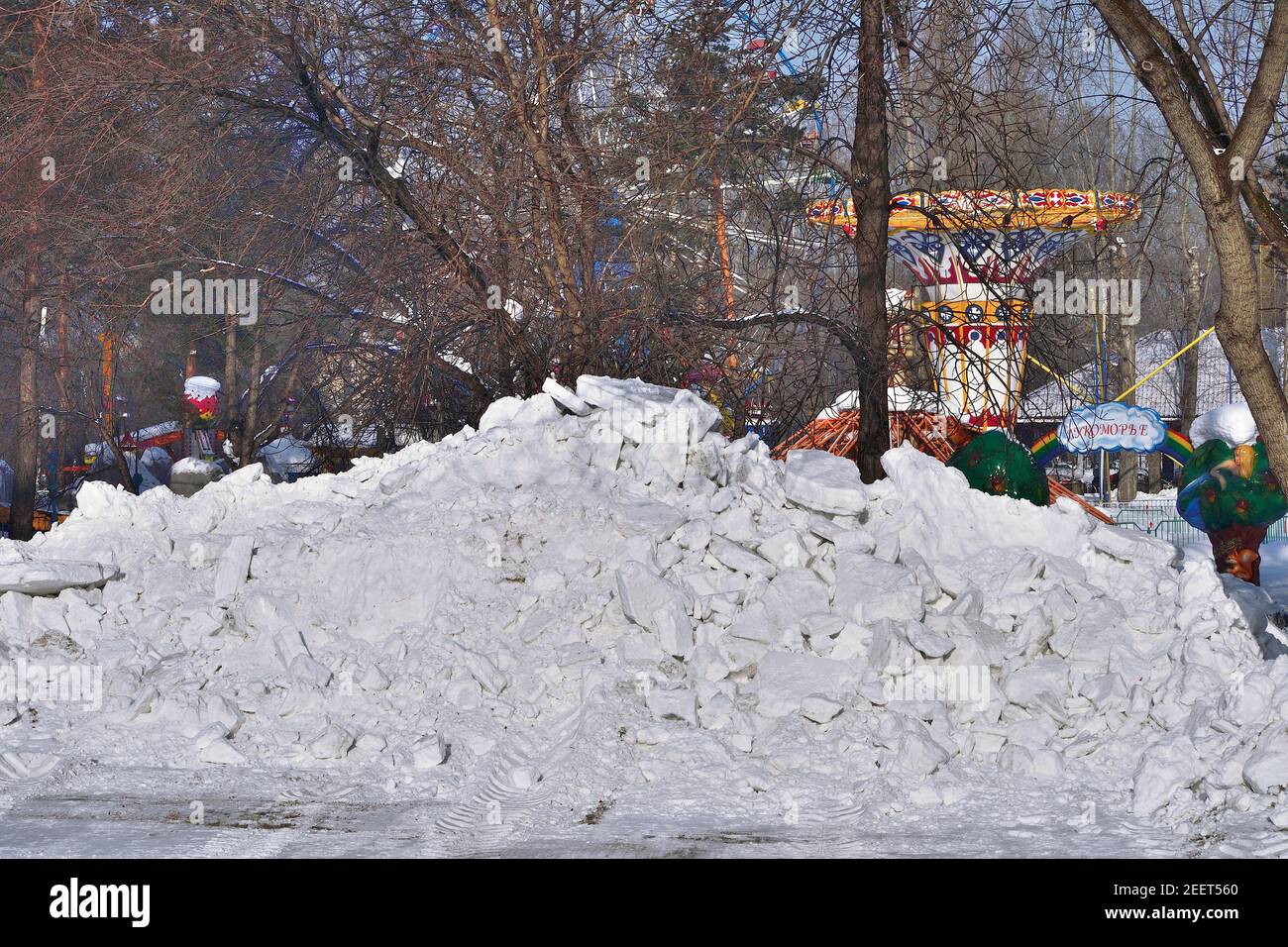 Snowdrift in the city park. Municipal communal services are cleaning snow on roads and alleys of city park. High snowdrift after snowfall or blizzard Stock Photo