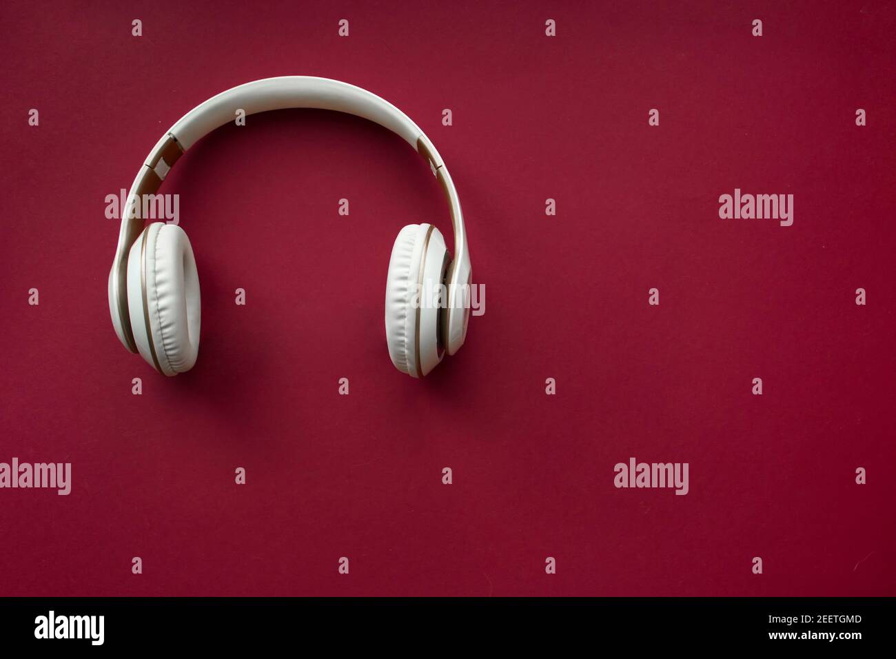 White wireless headphones on red background. Top view. Stock Photo