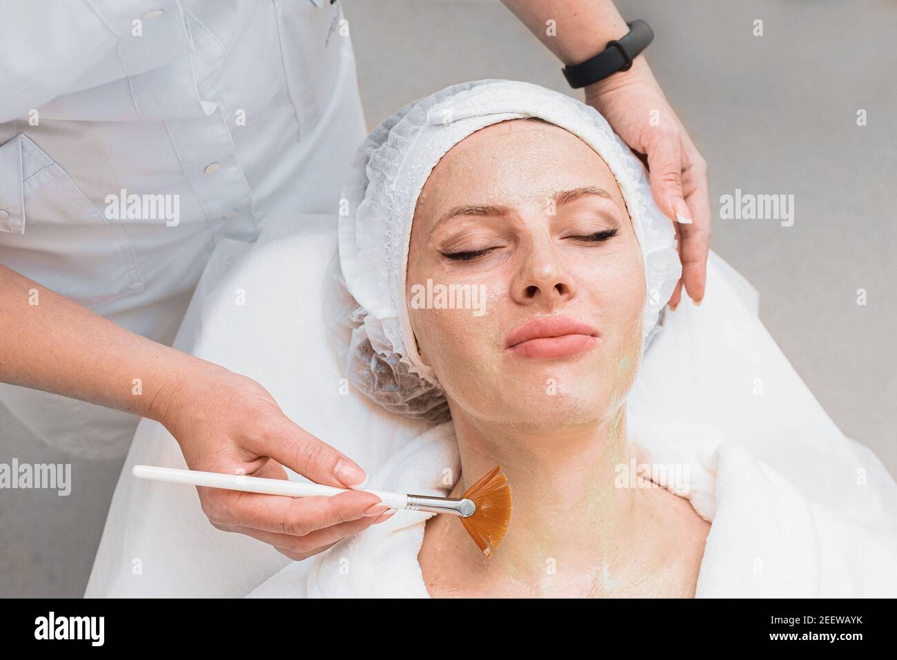 Application of an enzyme mask with a brush on a woman's face top view