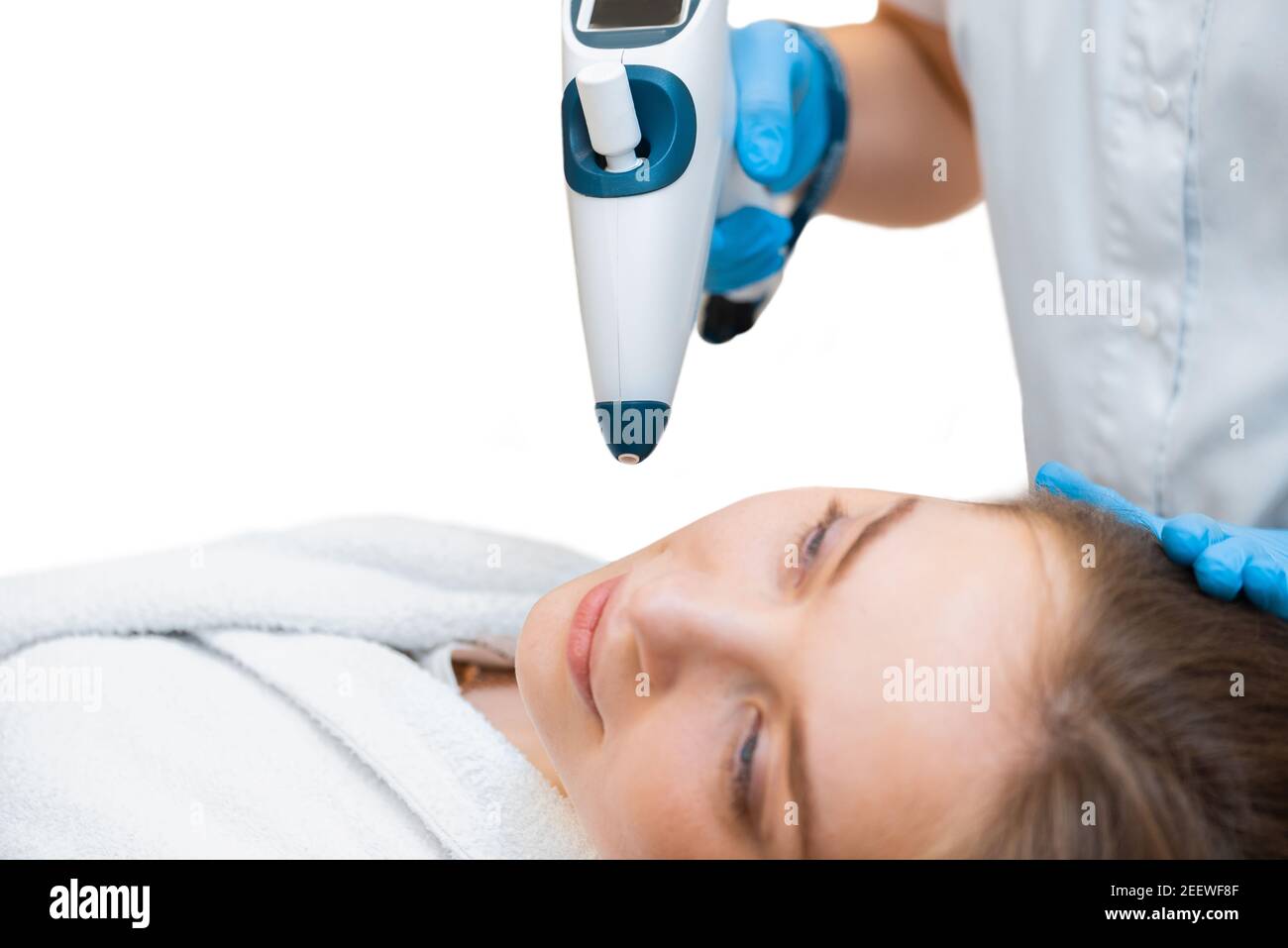 A beautiful girl is doing an anti-age cool lifting procedure with a non-injection gun on an isolated background. Stock Photo