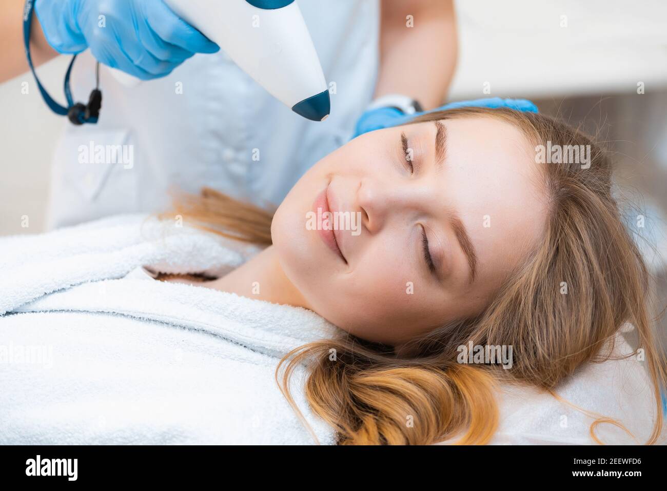 A beautiful attractive girl gets a cool lifting procedure with a non-injection carbon dioxide gun. Stock Photo