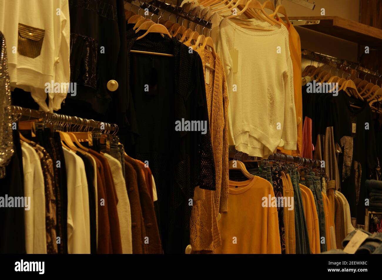 Close up of multicolored clothes hanging on rack at market. Stock Photo