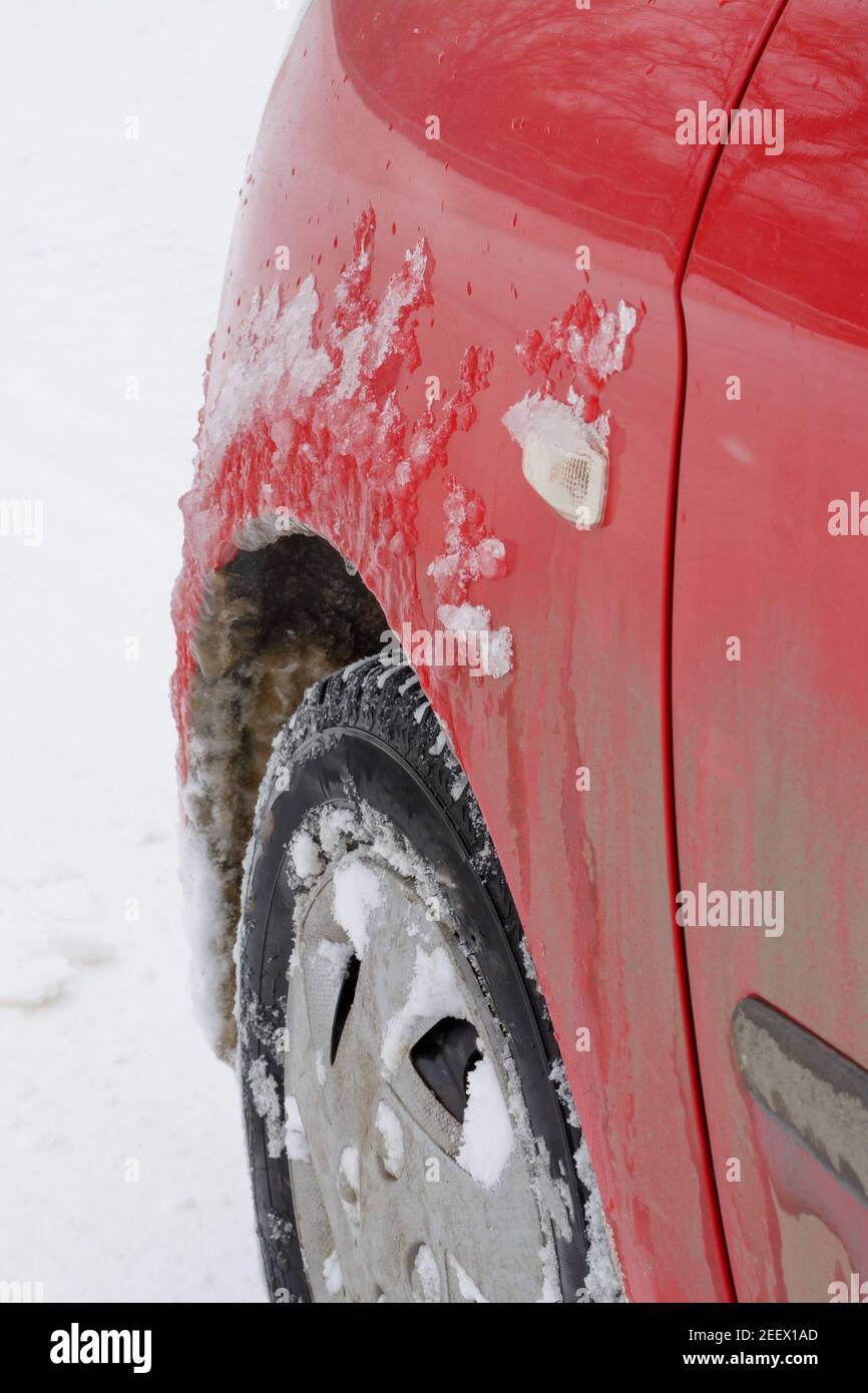 Ice on wing of car in winter. Snow stuck on wheel tire. Concept of dangerous driving in extreme cold and bad weather. Stock Photo